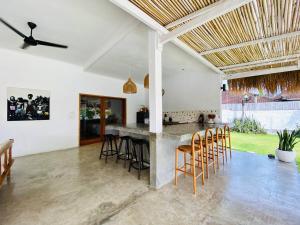 an open kitchen and living room with a bar with stools at Villa Stari in Canggu