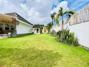 a yard with a white house and palm trees at Villa Stari in Canggu