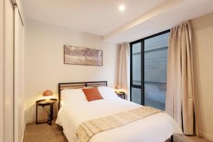 Brand New, Central & Spacious on Victoria Street في ويلينغتون: غرفة نوم بها سرير ونافذة كبيرة