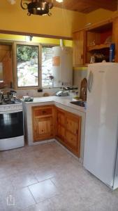 Una cocina con refrigerador blanco y gabinetes de madera. en Cabaña Rodar 2, en Villa Pehuenia