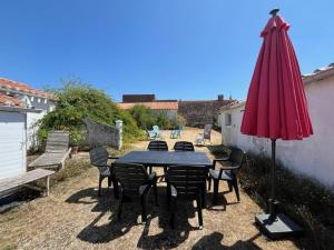 un patio con tavolo, sedie e ombrellone di Maison rénovée au cœur de Brem, 4 couchages, jardin, WIFI - FR-1-231-340 a Brem-sur-Mer