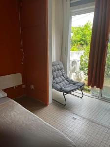 a bedroom with a chair in front of a window at Villa Ludger-Rose in Le Moule