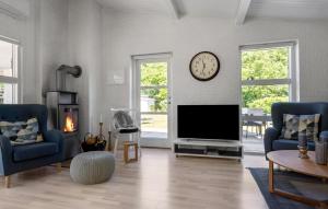 a living room with a tv and a clock on the wall at Gorgeous Home In Sydals With Sauna in Neder Lysabild