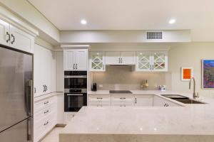 uma cozinha branca com armários e eletrodomésticos brancos em Mirage Resort Villa 105 with access to Sheraton Facilities em Port Douglas