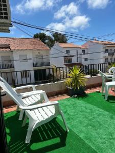 un patio con due sedie bianche su un prato verde di Casa Ana a Nazaré