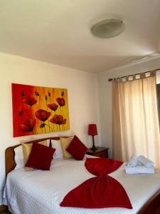 una camera con 2 letti con cuscini rossi e un quadro di Casa Ana a Nazaré