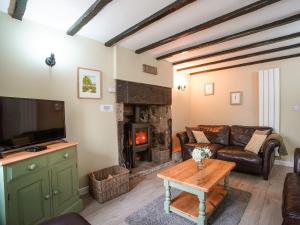 a living room with a couch and a fireplace at Fern Cottage in Bradwell