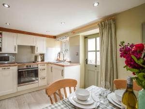 a kitchen with white cabinets and a table with chairs at Fern Cottage in Bradwell +22 photos