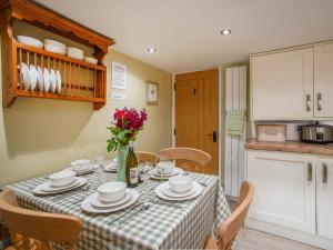 a kitchen with a table with plates and flowers on it at Fern Cottage in Bradwell