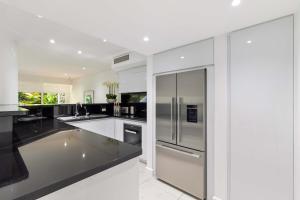 uma cozinha branca com um frigorífico de aço inoxidável em Mirage Resort Villa 116 with access to Sheraton Facilities em Port Douglas
