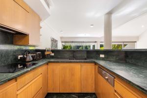 uma cozinha com armários de madeira e uma bancada em Mirage Resort Villa 124 with access to Sheraton Facilities em Port Douglas