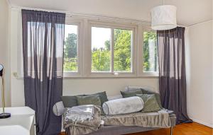 a living room with a couch and two windows at Beautiful Home In Flyinge in Flyinge