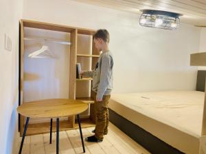 a boy standing in a room with a bed and a table at Ziegelgarten in Schwanau