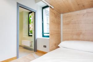 Schlafzimmer mit einem weißen Bett mit einem Kopfteil aus Holz in der Unterkunft A Room In The City Hostel in San Sebastián