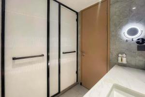 a bathroom with a shower door and a sink at Holiday Inn Shanghai Nanjing Road by IHG in Shanghai
