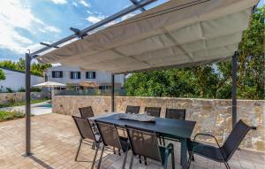 a patio with a black table and chairs under a large umbrella at Nice Apartment In Medulin in Medulin