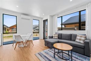 una sala de estar con un sofá, una mesa y sillas en Stylish 1BR Escape Near Remarks, en Queenstown Airport