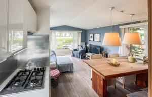 a kitchen and living room with a table and a stove at 2 Bedroom Nice Home In Lauwersoog in Lauwersoog