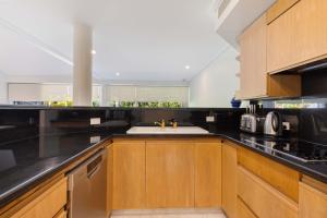 Una cocina con gabinetes de madera y un fregadero. en Mirage Resort Villa 138 with access to Sheraton Facilities, en Port Douglas