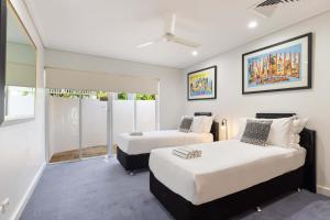 Un dormitorio con dos camas y una ventana. en Mirage Resort Villa 144 with access to Sheraton Facilities, en Port Douglas