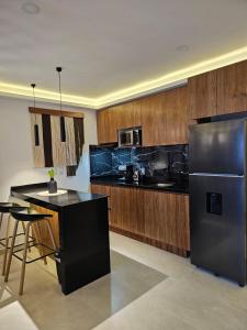 a kitchen with a black refrigerator and wooden cabinets at 1BR Comfort and style, near 5th Avenue with Pool in Playa del Carmen