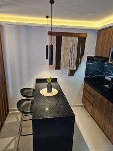 a kitchen with a black counter and some chairs at 1BR Comfort and style, near 5th Avenue with Pool in Playa del Carmen