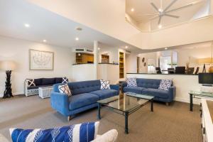 a living room with blue couches and a table at Mirage Resort Villa 179 with access to Sheraton Facilities in Port Douglas