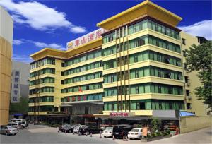 un gran edificio amarillo con coches aparcados en un aparcamiento en Guangzhou Junshan Hotel - Shuttle bus for Canton Fair, en Guangzhou