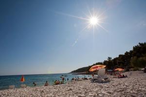 a group of people on a beach with the sun at Luxurious Apartments Maslina with Beach in Milna