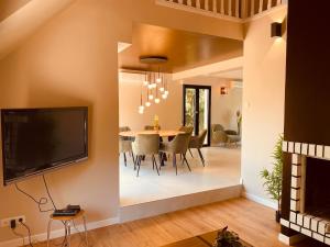 a living room with a dining room table and a tv at Villa La perle des Sylves in Neufchâtel-Hardelot