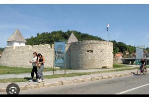 two women standing on a sidewalk next to a castle at Camping Nori-Una in Hrvatska Kostajnica