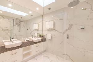 a white bathroom with two sinks and a shower at Mirage Resort Villa 422 with access to Sheraton Facilities in Port Douglas