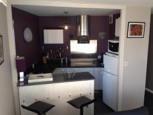 a kitchen with purple walls and a counter with stools at Duplex proche plage et centre ville in Concarneau