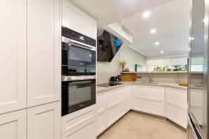 a kitchen with white cabinets and stainless steel appliances at Mirage Resort Villa 432 with access to Sheraton Facilities in Port Douglas