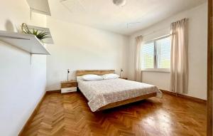 a white bedroom with a bed and a wooden floor at Lovely Apartment In Katuni With Wifi in Katuni