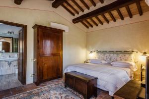 a bedroom with a bed and a bathroom with a sink at Villa Acquaviva Wine Resort in Montemerano