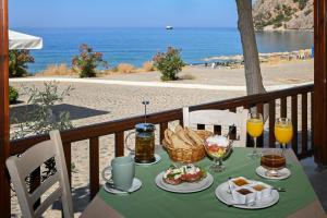 a table with food on a balcony with a view of the beach at Calypso in Agia Roumeli