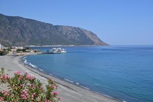 a boat in the water next to a beach at Calypso in Agia Roumeli