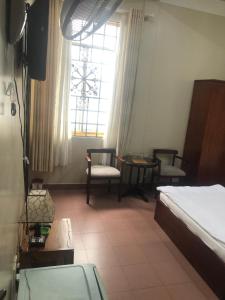 Un dormitorio con una cama y sillas y una ventana. en Bảo Thịnh, en Da Lat
