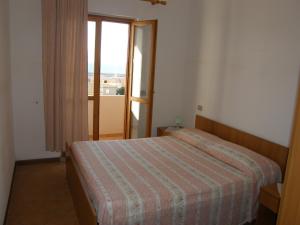 1 dormitorio con 1 cama y puerta con ventana en Isola Rossa Appartamenti Superior, en Isola Rossa