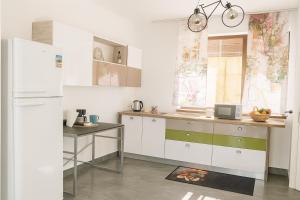 a kitchen with white cabinets and a table and a refrigerator at PlaiulGreenbike in Deva +21 photos
