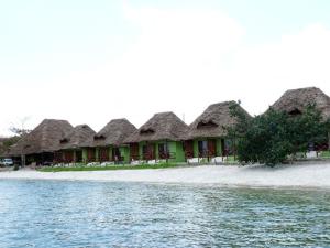 a row of houses with thatched roofs on a beach at Pemba Misali Sunset Beach in Wesha