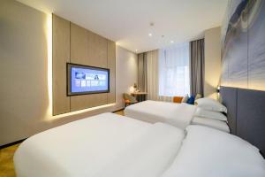 a hotel room with two beds and a flat screen tv at Borrman Hotel Zhangzhou Baolong Plaza in Zhangzhou +227 photos