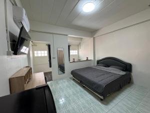 a bedroom with a bed and a flat screen tv at Tin Guest House & Laundry in Jomtien Beach