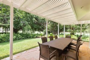 a patio with a table and chairs under a white pergola at Mirage Resort Villa 112 with access to Sheraton Facilities in Port Douglas