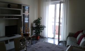 ein Wohnzimmer mit einem Tisch, einem Sofa und einem TV in der Unterkunft Cristina Apartment in Verona