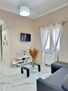 a white living room with a couch and a tv at Aiginetan Apartments in Aegina Town