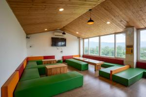 a room with green couches and tables and windows at Hotel Yog Ganga Retreat in Rishīkesh