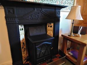 a black fireplace with a lamp and a table at Oswin Cottge in Alnwick