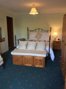 a bedroom with a large bed with white sheets and pillows at Orchard Manor in Probus
